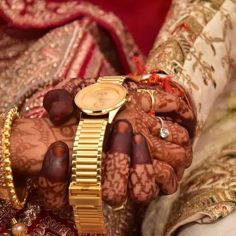 Hands with henna tattoos holding a golden watch